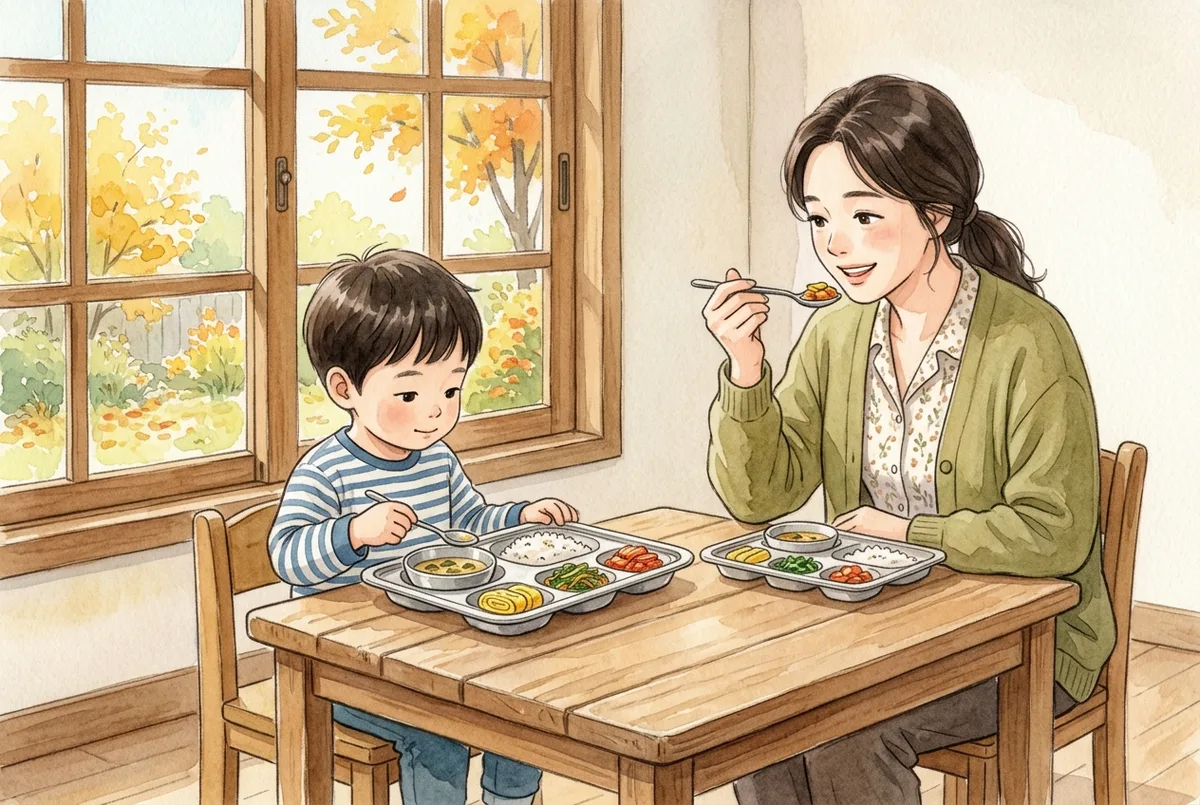 식판 앞에 앉은 아이 맞은편에서 선생님이 같은 반찬을 맛보며 미소 짓는 모습 (AI로 만든 그림)